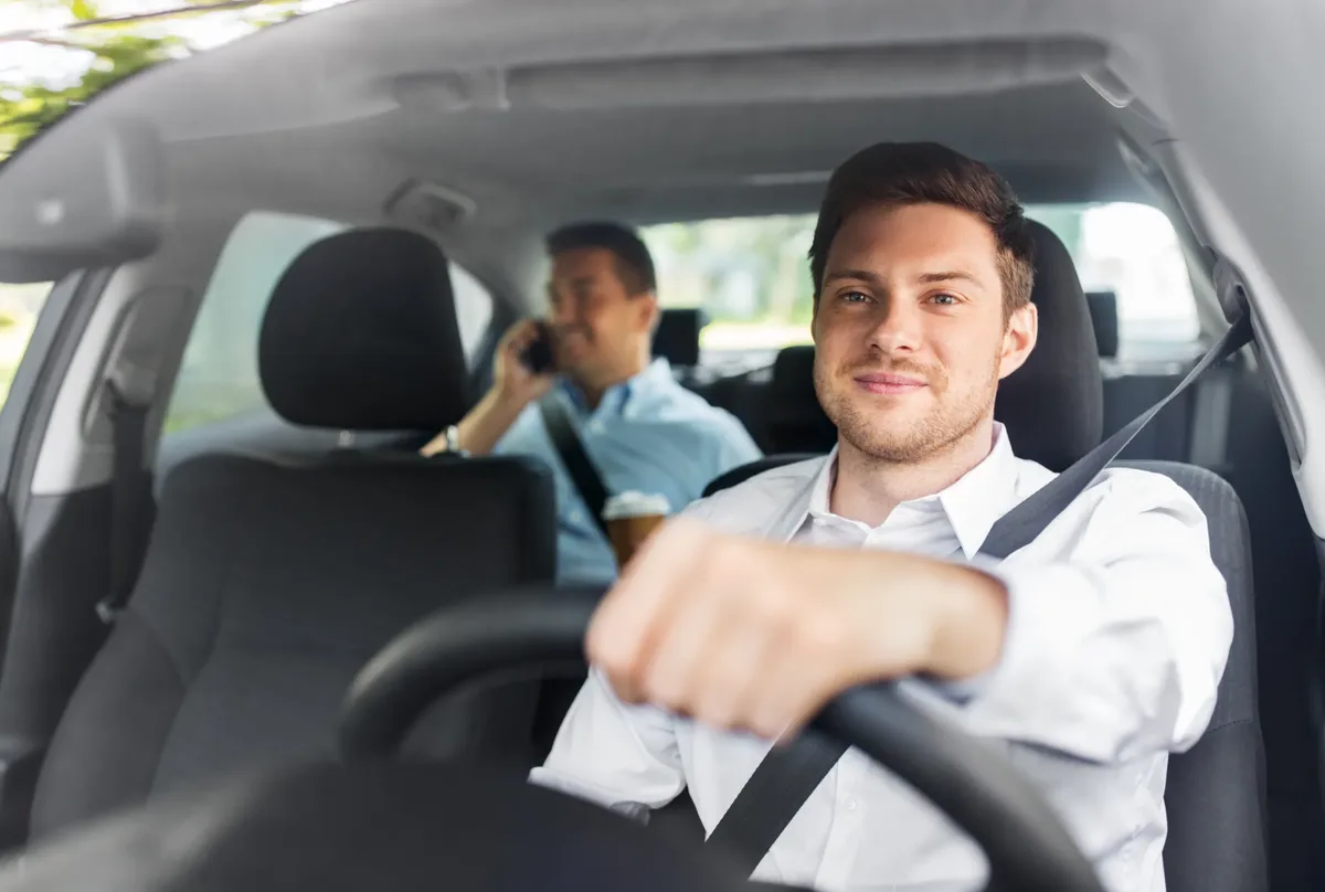 Driver and passenger travelling in a modern vehicle with three-point seat belts fastened across the shoulder