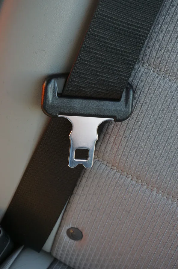 Metal seat belt tongue plate with locking slot seated in its moulded webbing guide
